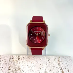 Detail view of the red square dial quartz watch with smooth silicone strap and gold case.