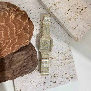 Detailed close-up of a women's square rhinestone quartz watch in gold tone with sparkling crystals.