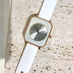 Detail view of women square quartz watch with white silicone strap and silver digital dial.