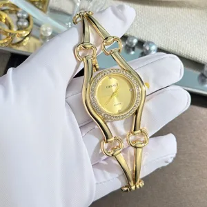 Detailaufnahme einer luxurioesen goldenen Quarzuhr mit einzigartigem Pferdetrensen-Design und Strass.