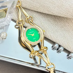 Gruenes Zifferblatt Quarz Damen Armbanduhr mit goldenem Trensen Armband und Straessteinen.