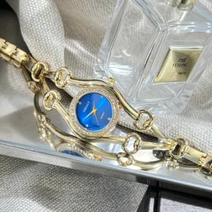 Elegante Damenuhr mit blauem Zifferblatt, Strasssteinen und goldenem Gliederarmband im Detail.