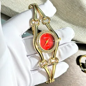 Luxus Damen Quarzuhr mit rotem Zifferblatt, Strasslünette und goldenem Kettenarmband.