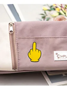 Vista dettagliata di una simpatica spilla smaltata emoji dito medio su astuccio in tela casual.