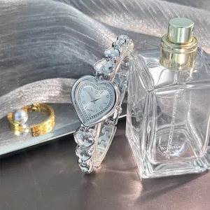 Gros plan sur le détail de montre quartz cœur strass avec bracelet en cristal étincelant.