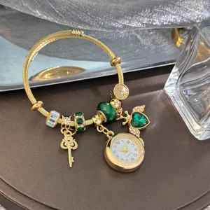 Gold charm bracelet with quartz watch, green crystal heart and key pendant for women.