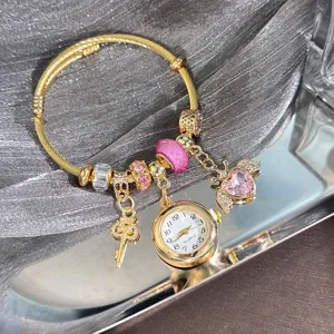Gold charm bracelet with quartz watch, heart key pendant and pink crystal beads.