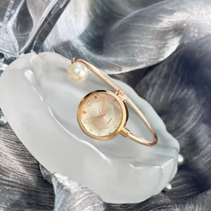 Elegante roségoldene Quarz Armreif Uhr mit Perle und glitzernden Kristallsteinen.