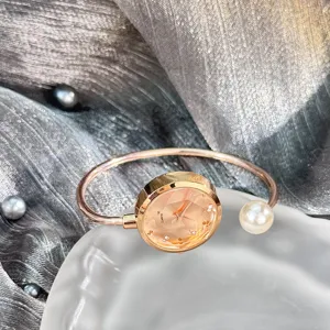 Detailansicht der roségoldenen Armreif-Uhr mit facettiertem Glas-Zifferblatt und Perle.