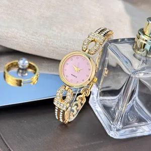 Elegante Damen Strass Quarz Uhr mit rosa Glitzer Zifferblatt und goldenem Armband.