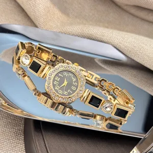 Close-up detail of luxury gold-tone quartz wristwatch with rhinestones and black gemstones.