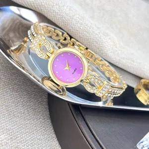 Detaillierte Nahaufnahme einer goldenen Strass-Armbanduhr mit funkelndem lila Zifferblatt.