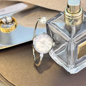 Detailaufnahme der eleganten Armbanduhr mit funkelnden Strasssteinen und Perle auf dem Tisch.