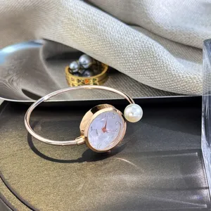 Nahaufnahme des roségoldenen Armbanduhr-Details mit funkelnden Kristallen und Perle.