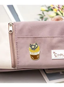 Close-up detail of a cute cartoon cat burrito enamel pin, perfect for bag or clothing decor.
