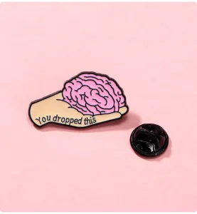 Enamel pin detail showing funny hand holding brain design with secure metal clutch back.