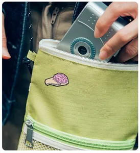 Close-up detail view of the funny brain enamel pin attached on green bag, creative metal badge.