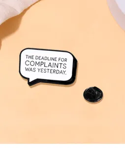 Detail view of a black and white enamel speech bubble brooch with a funny English slogan pin.