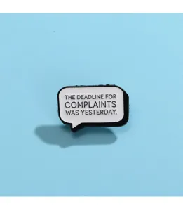 Close up of speech bubble enamel pin featuring funny quote lettering design, detailed view.