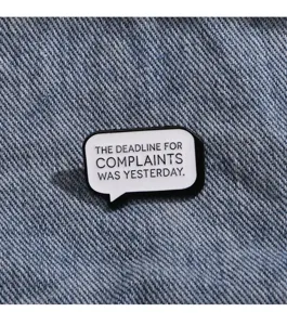 Black and white speech bubble slogan enamel pin detail shot showing funny quote accessory.