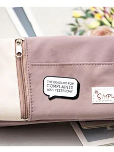 Enamel pin detail showing black and white speech bubble slogan design for bags and clothes.