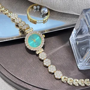 Close-up of a glamorous rhinestone gold quartz watch with a vibrant green dial and delicate chain.