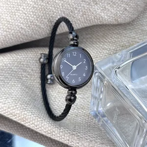 Detailansicht der schwarzen Armreif-Quarzuhr für Damen mit stilvollem Kordelarmband und Zifferblatt.