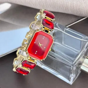 Detailaufnahme einer luxuriösen Damen-Viereckuhr mit roten Edelstein-Gliedern und Goldgehäuse.