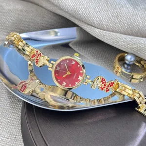 Elegante Damen Quarzurhr mit rotem Zifferblatt und funkelndem Schmetterling Armband Detail.