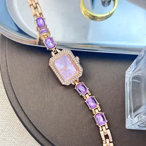 Roségold Damenuhr mit lila Kristallsteinen und funkelnden Strasssteinen auf rechteckigem Zifferblatt.