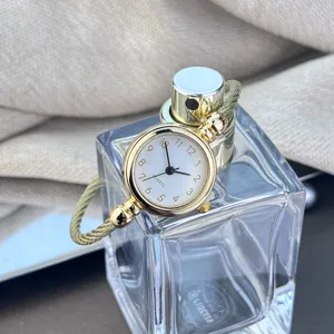 Detailaufnahme einer minimalistischen goldenen Armbanduhr mit Quarzwerk und schickem Armreif.