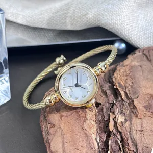 Nahaufnahme einer goldenen Quarzuhr mit Kordelarmband und klassischem runden Zifferblatt.