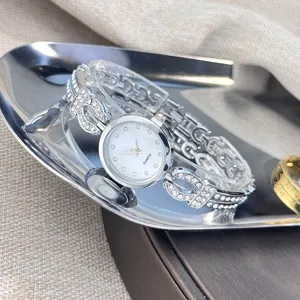 Nahaufnahme einer Damen Quarz Strass Uhr, glänzendes Metall Armband, silbernes Zifferblatt.