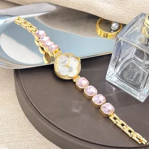 Vista detallada del reloj de cuarzo trébol de lujo con eslabones de pulsera de cristal rosa.