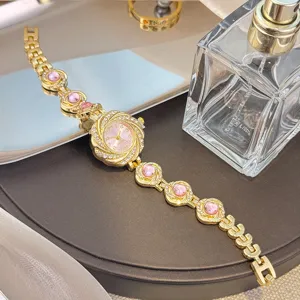 Elegante goldene Damen Quarz Armbanduhr mit wunderschönen rosa Steinen und stilvollem Zifferblatt.