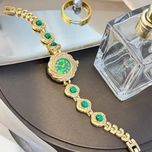 Elegante goldfarbene Damen Quarzuhr mit grünen Schmucksteinen und funkelnden Strasssteinen.