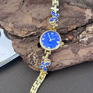 Schicke goldfarbene Quarzuhr mit blauem Zifferblatt und funkelndem Schmetterlings-Gliederarmband.