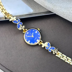 Nahaufnahme Detail der Damenuhr, goldenes Armband mit blauen Schmetterlingen und Strass.