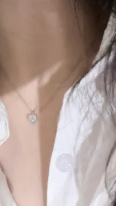 Nahaufnahme einer silbernen Herz-Moissanit-Halskette am Hals, elegant und sehr zart.