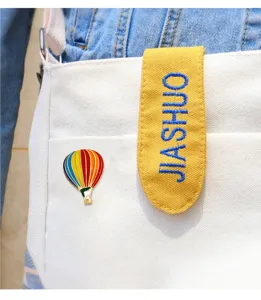 Hot air balloon brooch close-up, colorful enamel lapel pin detail on white canvas bag
