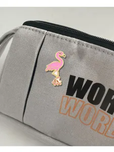 Detailed view of a cute pink flamingo enamel brooch pinned on a gray fabric bag nicely.