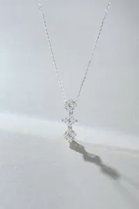 Close-up detail shot of triple clover tassel pendant necklace, sparkling paved stones design.