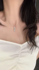 Detailed view of a silver moissanite clover necklace featuring sparkling heart stones.