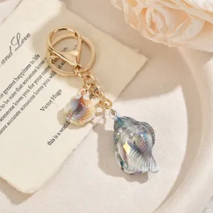 Détail de porte-clés doré élégant avec pendentif coquillage en acrylique dégradé coloré.