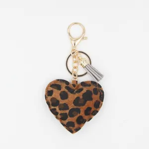 Close-up detail of a chic leopard print heart keychain with gold metal clasp and tassel charm.