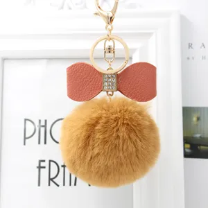 Fluffy faux rabbit fur pom pom keychain with elegant PU leather bow and gold metal hardware.