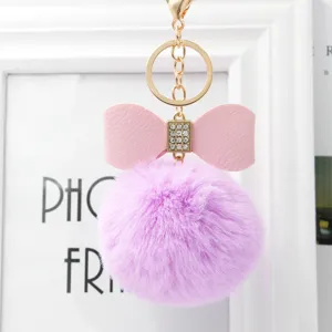 Cute purple faux fur pom pom keychain with pink leather bow and sparkling rhinestones.
