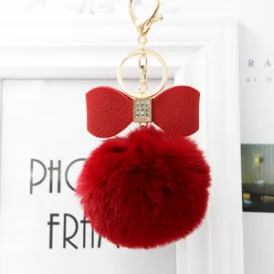 Close-up view of the red fluffy fur ball keychain with a rhinestone bow and gold hardware.