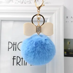 Blue fluffy pom pom keychain with chic bow and rhinestones, perfect bag charm accessory.
