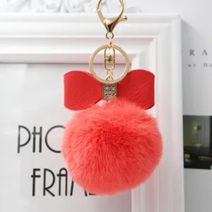 Red faux fur pom pom keychain with bowknot and golden metal clasp for bags and keys.